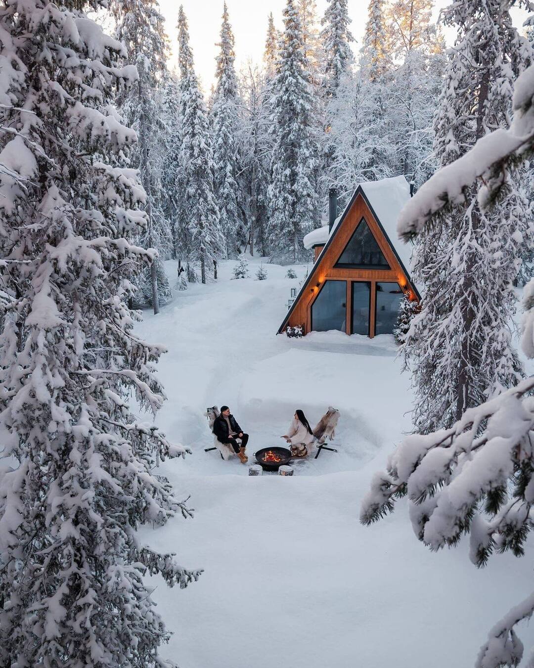 A forest cabin glowing warm in the forest at dusk.