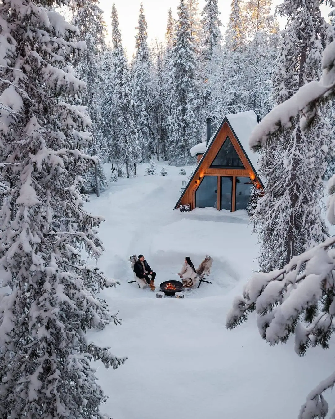 An A-frame cabin glowing warm in the forest at dusk.