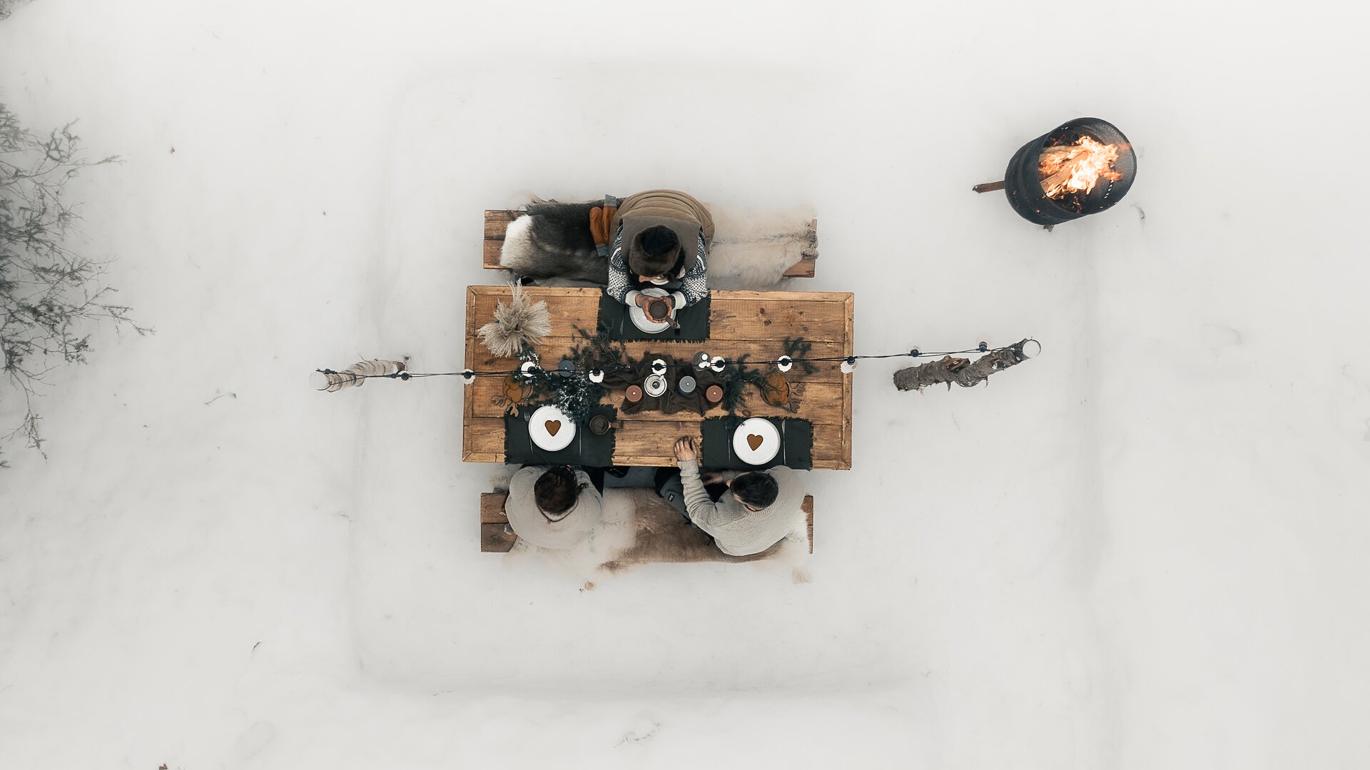 A small bowl of hot soup set on a wooden board in the snow.
