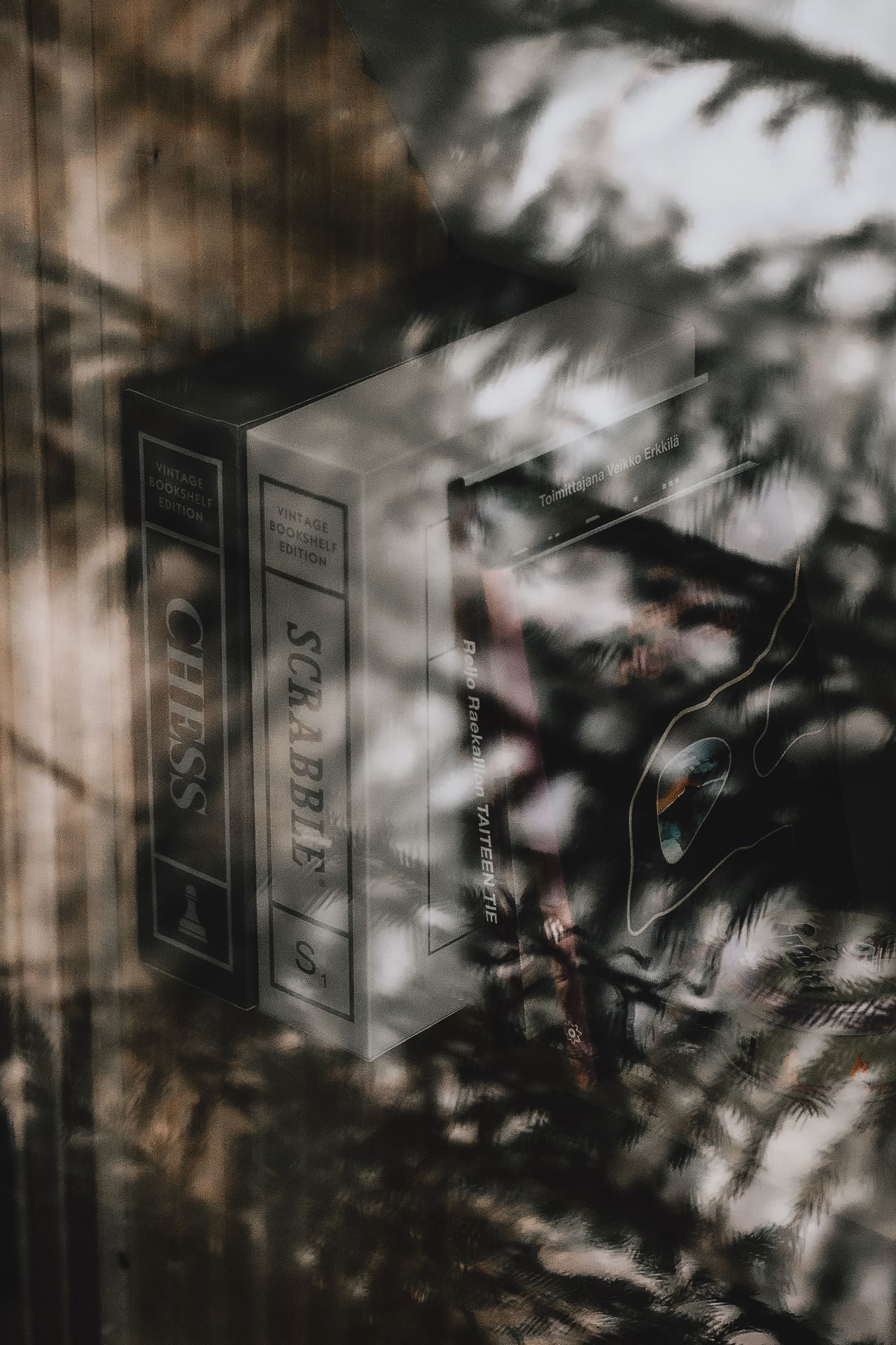 Vintage Bookshelf editions of Chess and Scrabble in the cabin, snowy pines reflected in the glass beyond.