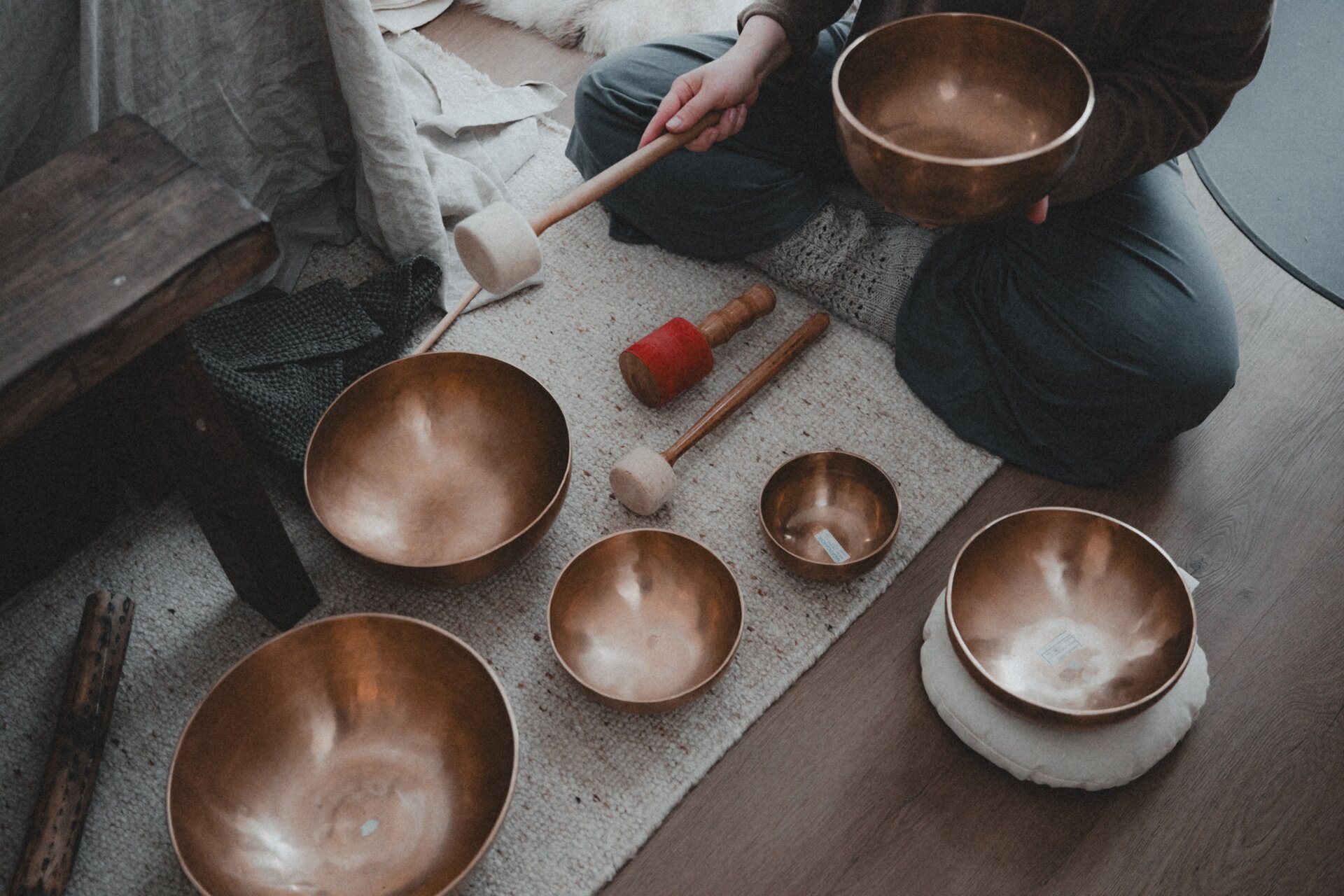 Singing bowls and koshi bells arranged on a soft linen cloth inside the cabin, ready for a sound bath.
